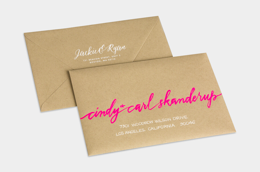 Modern kraft paper wedding envelopes with bold neon pink script addressing on the front and classic white calligraphy return addressing on the back, blending playful contemporary style with rustic texture.