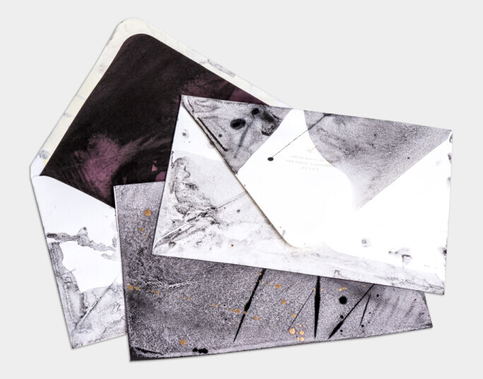 Modern abstract wedding invitation envelopes featuring black, white, and deep plum marble textures with metallic gold foil accents and watercolor accents.